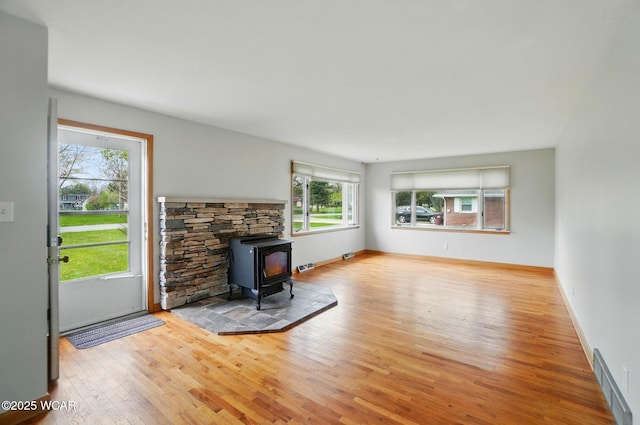 living area featuring baseboards, visible vents, wood finished floors, and a wood stove