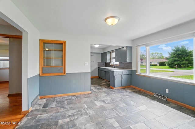 kitchen featuring a sink, visible vents, gray cabinets, and baseboards