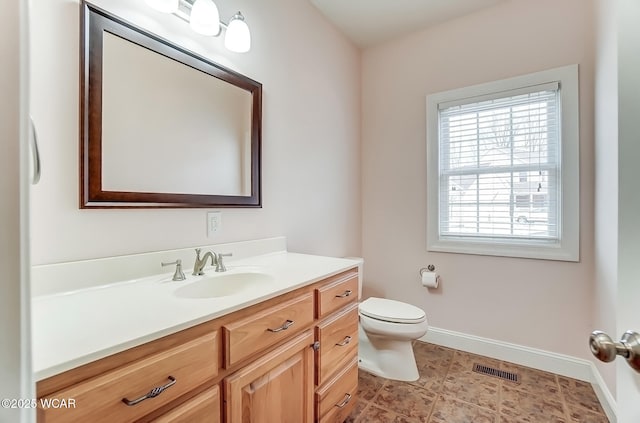 bathroom with toilet, vanity, visible vents, and baseboards