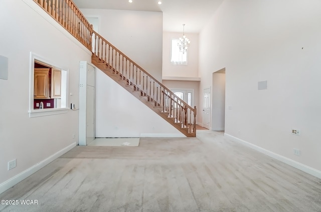 entryway with a high ceiling, stairway, light colored carpet, and baseboards