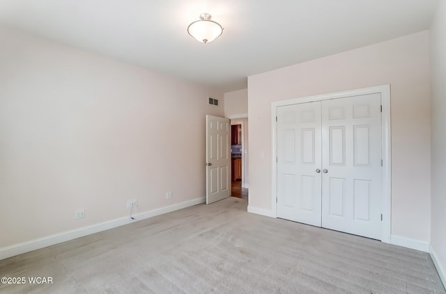 unfurnished bedroom with light colored carpet, a closet, visible vents, and baseboards