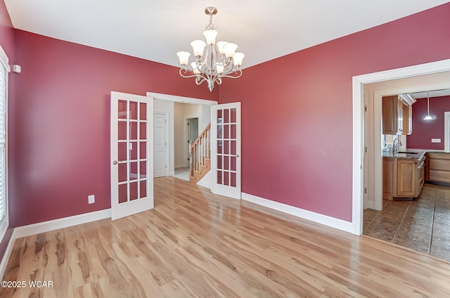 empty room featuring light wood-type flooring, a sink, and baseboards