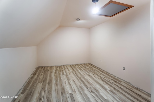 additional living space featuring lofted ceiling, light wood-style flooring, and attic access