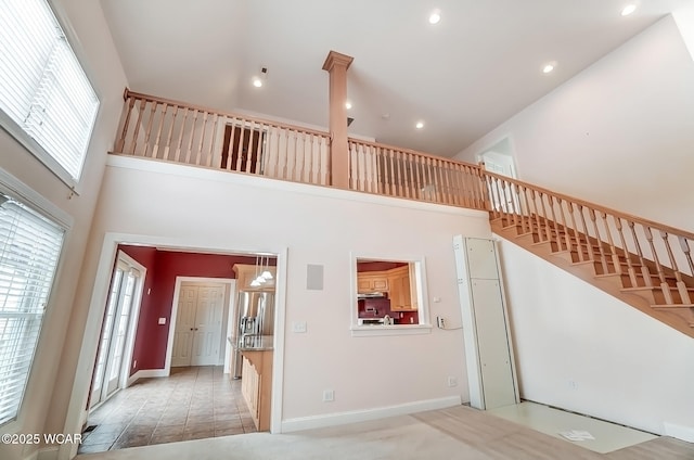 staircase with a towering ceiling, baseboards, and recessed lighting