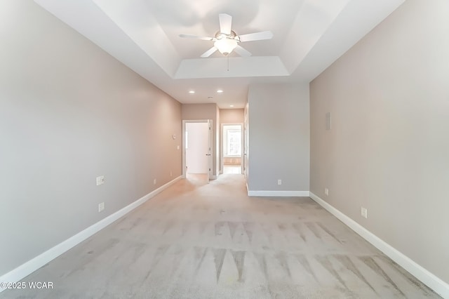 spare room with baseboards, light colored carpet, ceiling fan, a tray ceiling, and recessed lighting