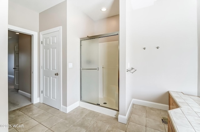 bathroom with a stall shower, tile patterned flooring, and baseboards