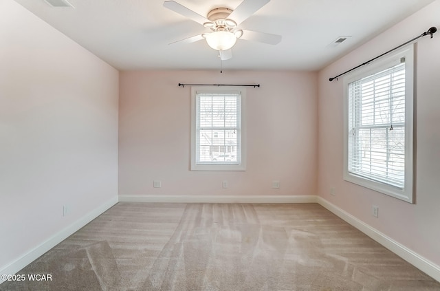 spare room featuring carpet floors, a ceiling fan, visible vents, and baseboards