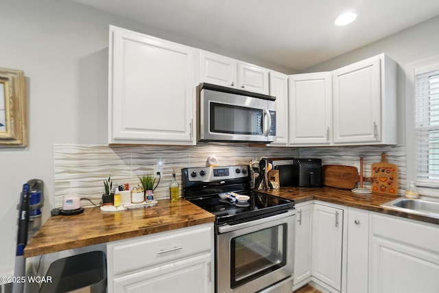 1826 W High St, Lima, OH 45805 - kitchen with appliances with stainless steel finishes, wood counters, backsplash, white cabinets, and recessed lighting