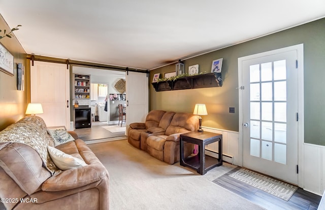 living room featuring a baseboard radiator, a barn door, and carpet flooring