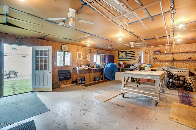 interior space featuring heating unit, ceiling fan, and a workshop area