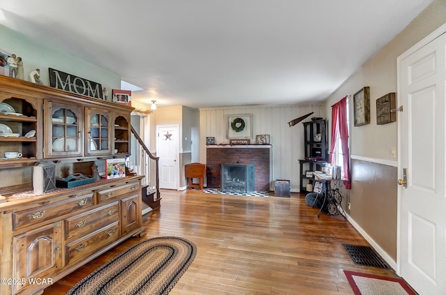 living room with a brick fireplace and hardwood / wood-style flooring