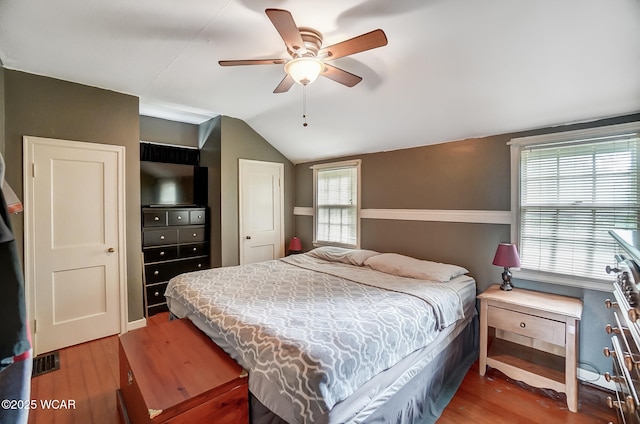 bedroom with vaulted ceiling, ceiling fan, hardwood / wood-style floors, and multiple windows