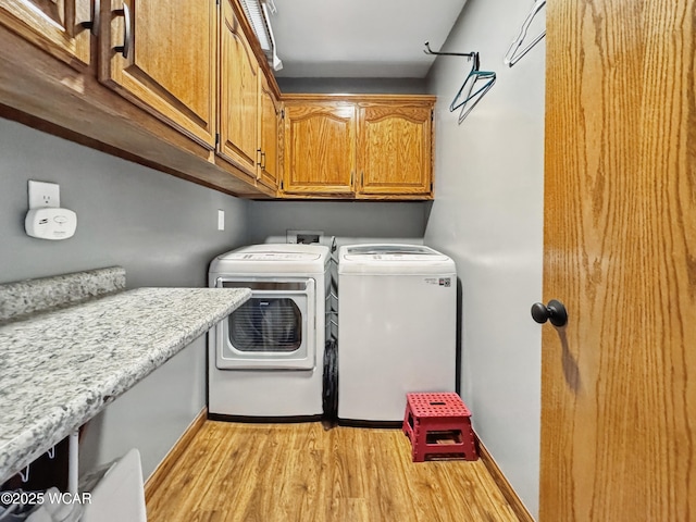laundry area featuring cabinet space, independent washer and dryer, and light wood finished floors