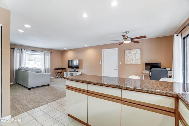 kitchen with light carpet, ceiling fan, white cabinetry, and light stone countertops