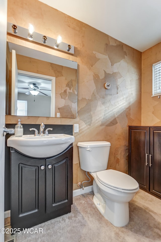 bathroom with toilet, vanity, and ceiling fan