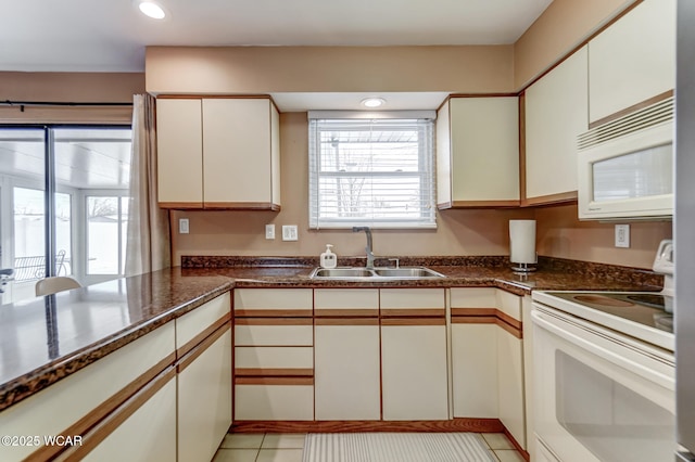 kitchen with white appliances, light tile patterned floors, sink, white cabinetry, and kitchen peninsula