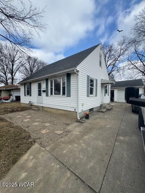 view of front of house with an outbuilding, driveway, roof with shingles, and entry steps