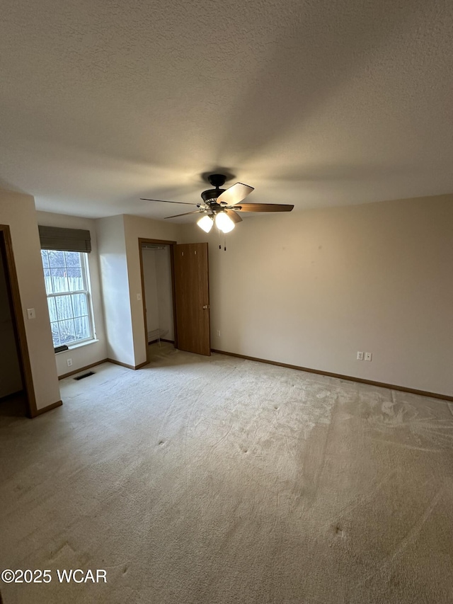 empty room featuring light carpet, ceiling fan, and a textured ceiling