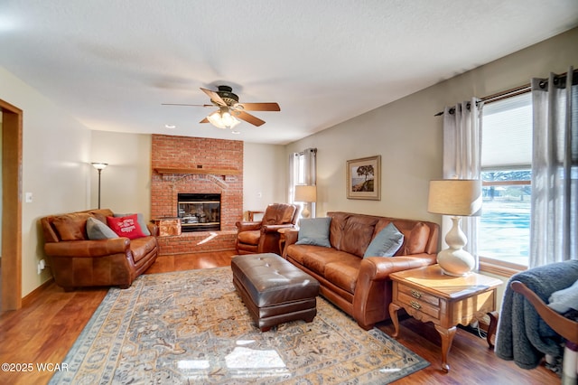 living room featuring hardwood / wood-style floors, a wealth of natural light, a brick fireplace, and ceiling fan