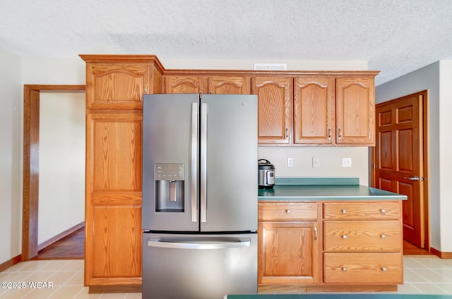 kitchen with stainless steel fridge with ice dispenser, light tile patterned floors, and a textured ceiling