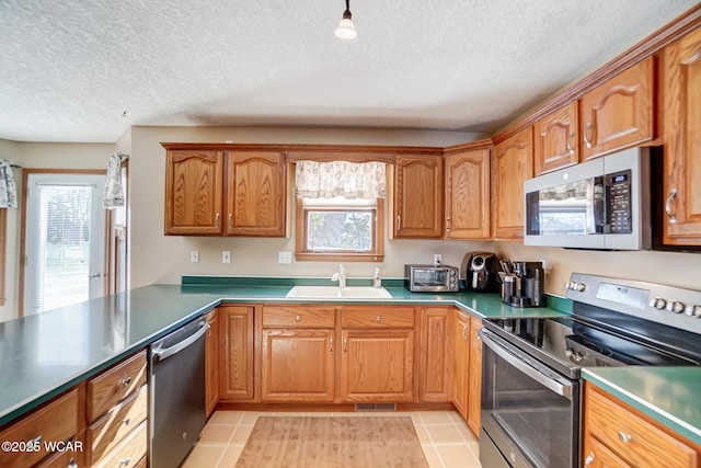 kitchen featuring light tile patterned flooring, sink, stainless steel appliances, a healthy amount of sunlight, and a textured ceiling