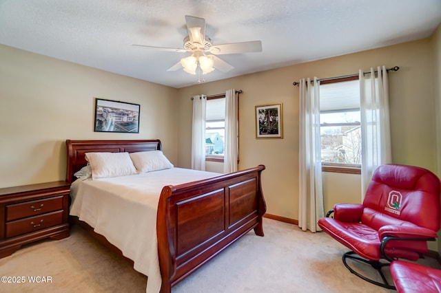 carpeted bedroom featuring multiple windows, a textured ceiling, and ceiling fan