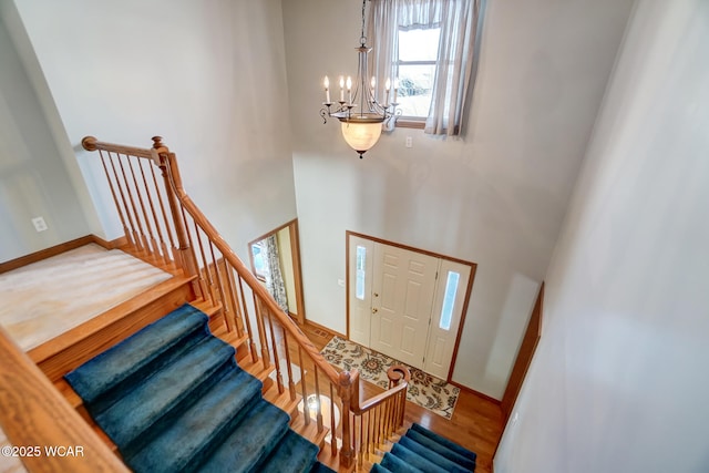 stairs featuring wood-type flooring and a chandelier