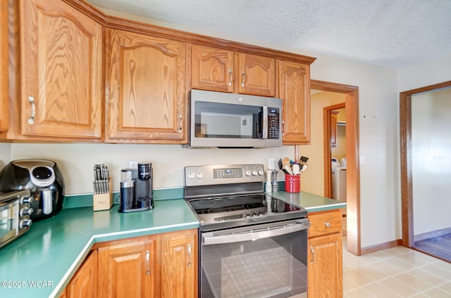 kitchen with stainless steel appliances, a textured ceiling, and light tile patterned flooring