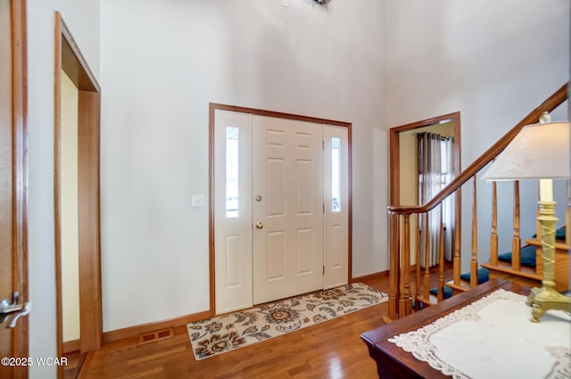 foyer entrance with hardwood / wood-style flooring and a towering ceiling