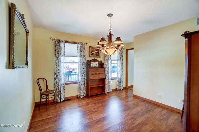 dining area with dark hardwood / wood-style flooring and an inviting chandelier