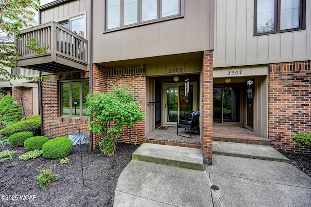 entrance to property with brick siding and a balcony