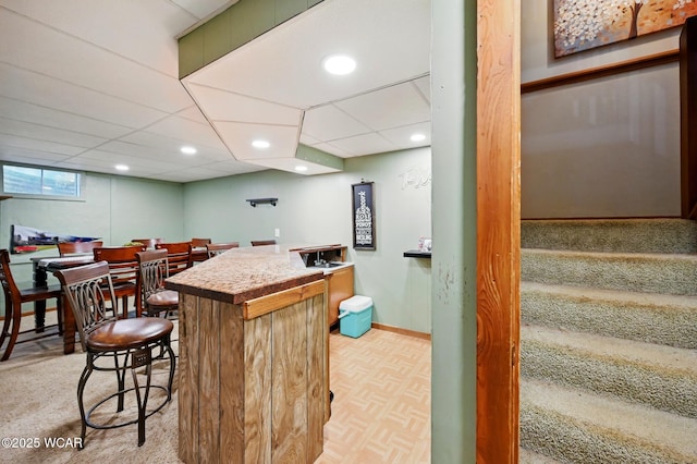 bar featuring a bar, stairs, baseboards, and recessed lighting