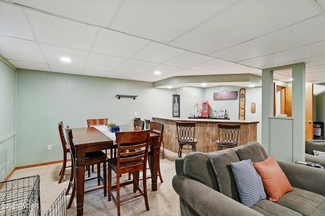 dining space featuring a dry bar, recessed lighting, baseboards, a paneled ceiling, and light colored carpet
