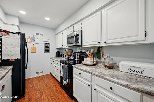kitchen featuring white cabinetry, black appliances, visible vents, and wood finished floors