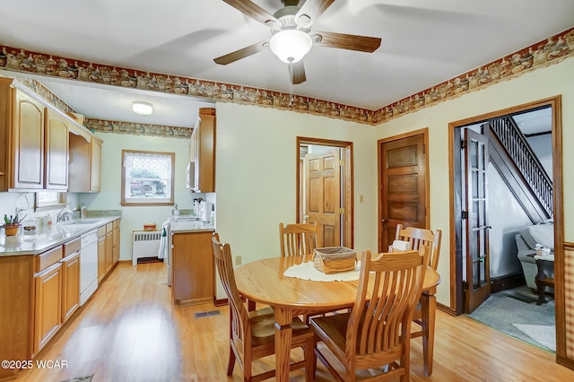 dining area with radiator, visible vents, baseboards, ceiling fan, and light wood-type flooring