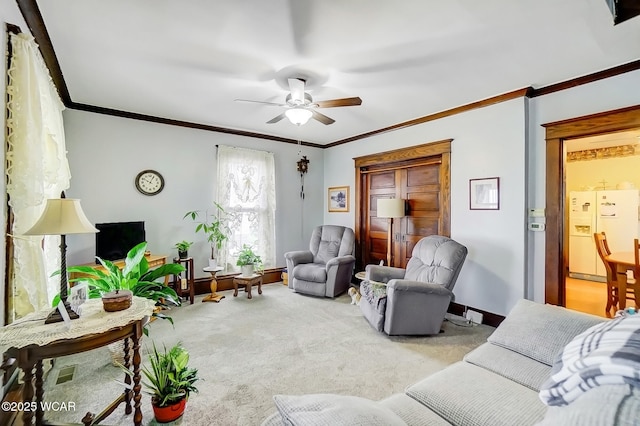 living area with carpet flooring, baseboards, a ceiling fan, and ornamental molding