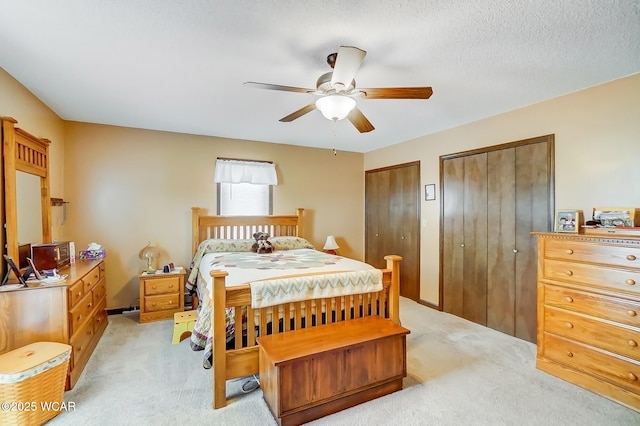 bedroom with two closets, a ceiling fan, and a textured ceiling