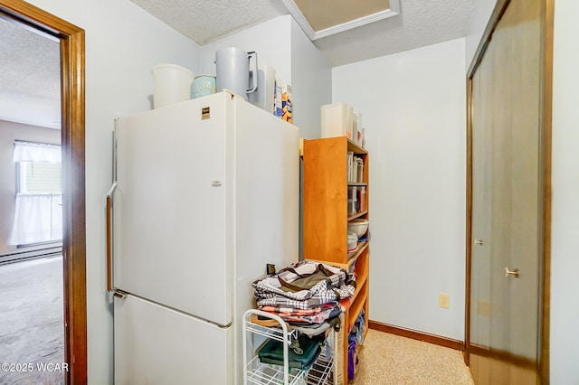 kitchen with carpet, baseboards, freestanding refrigerator, and a textured ceiling