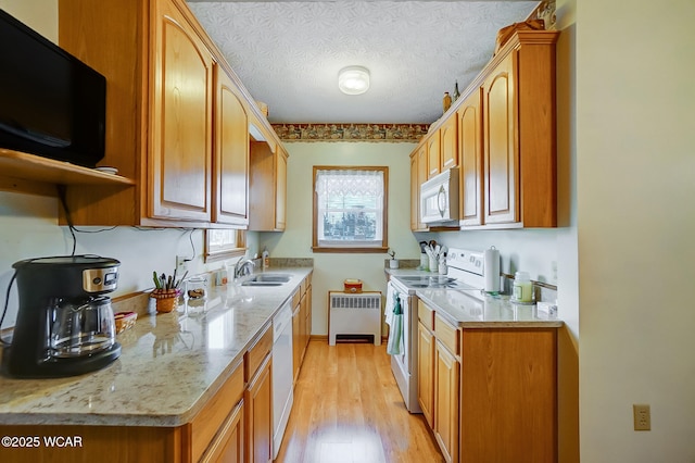 kitchen featuring radiator, light wood-style floors, white appliances, a textured ceiling, and a sink