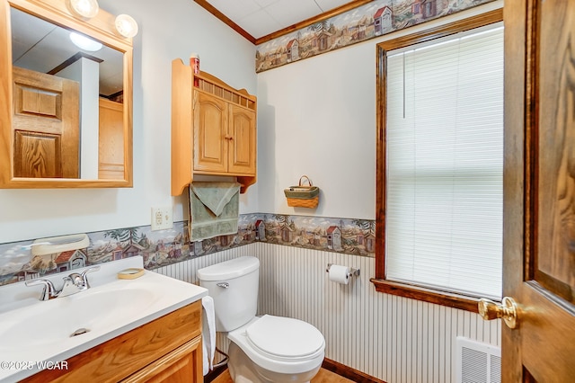 bathroom featuring visible vents, wallpapered walls, a wainscoted wall, toilet, and vanity