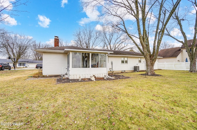 rear view of property with central AC and a lawn