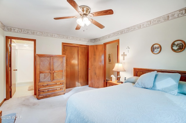 bedroom featuring ceiling fan, light colored carpet, ensuite bath, and a closet