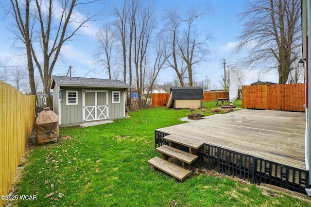view of yard with an outbuilding, a wooden deck, a shed, and a fenced backyard
