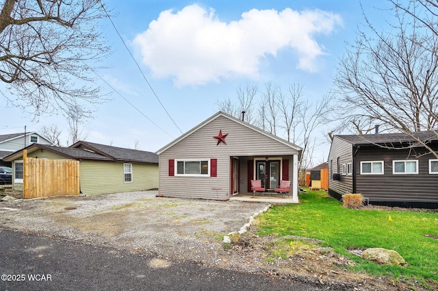bungalow featuring covered porch, fence, and a front lawn