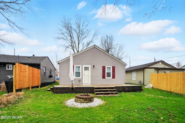 rear view of property with fence, a wooden deck, a yard, and a fire pit