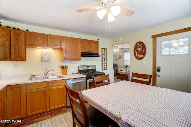 kitchen with a ceiling fan, light countertops, under cabinet range hood, a sink, and stainless steel appliances
