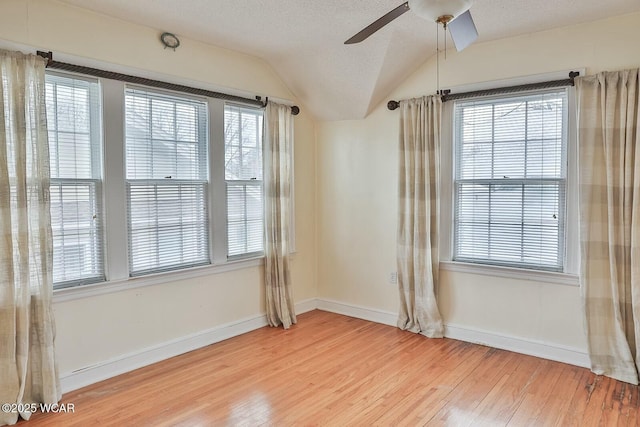 unfurnished room featuring lofted ceiling, a textured ceiling, wood-type flooring, and a healthy amount of sunlight