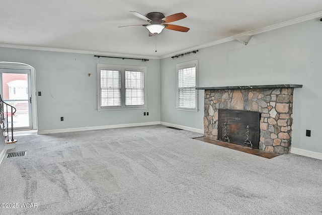 unfurnished living room featuring ceiling fan, ornamental molding, a fireplace, and carpet