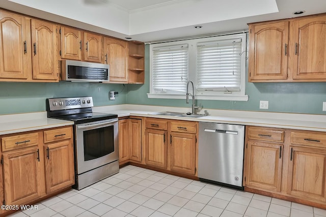 kitchen with a tray ceiling, sink, light tile patterned floors, and stainless steel appliances