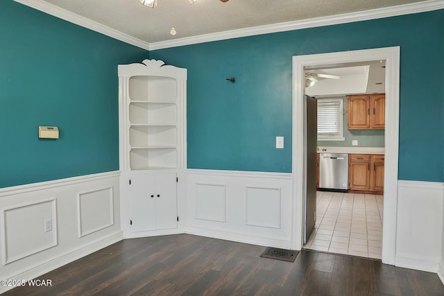 unfurnished dining area featuring dark wood-type flooring, built in features, ceiling fan, ornamental molding, and a textured ceiling